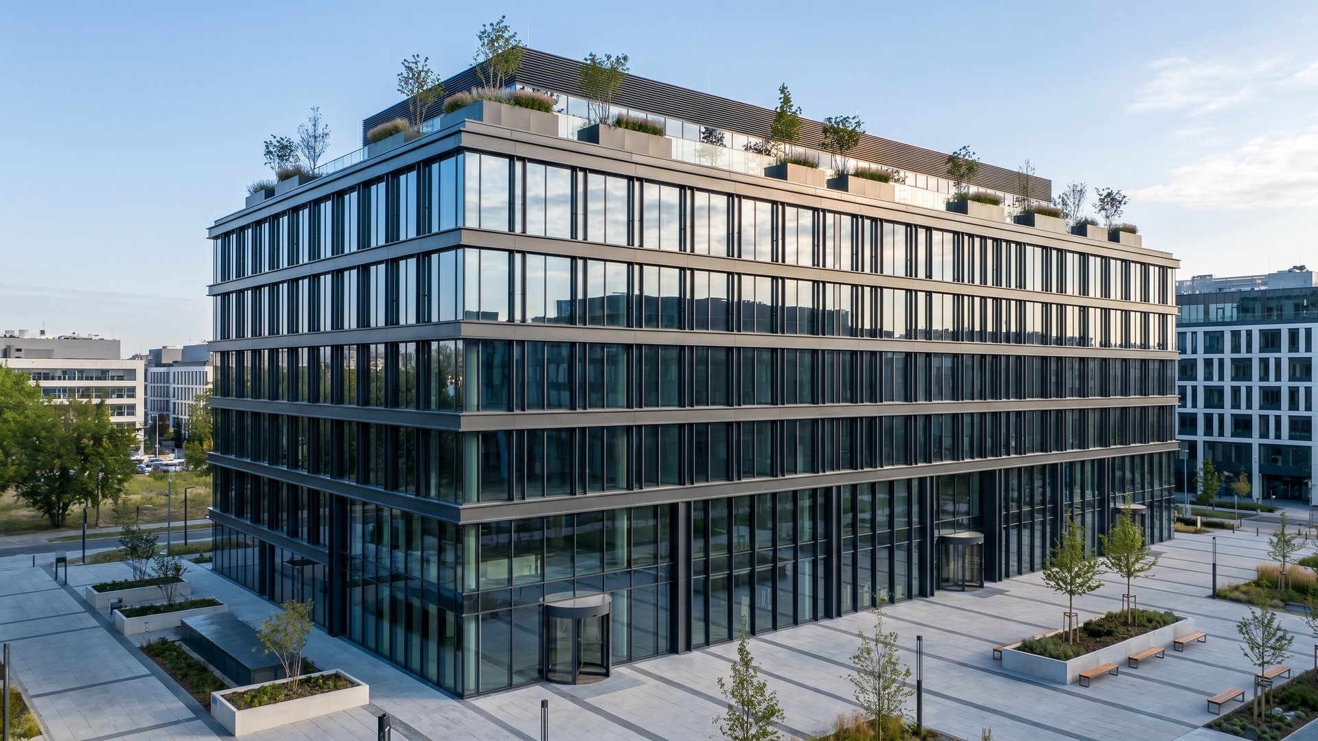 Biurowiec klasy A z fasadą curtain-wall, antracytowe szprosy aluminiowe, zieleń na dachu, obrotowe wejście